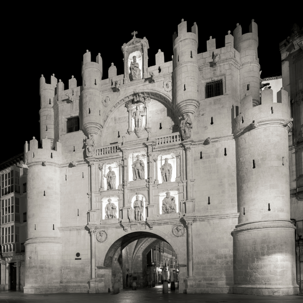 Arco de Santa María iluminado durante la noche en Burgos, en una fotografía en blanco y negro